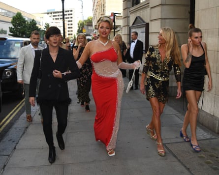 Temple in a red dress and several others walk along the pavement