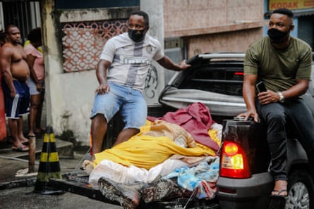 Residents remove bodies from Rio’s Complexo do Alemão favela on Friday after the police operation.