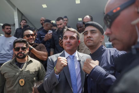 Flávio Bolsonaro surrounded by a small crowd of men, some in military clothing.