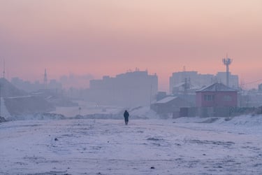 A person in the distance walks through a snowy semi-urban landscape