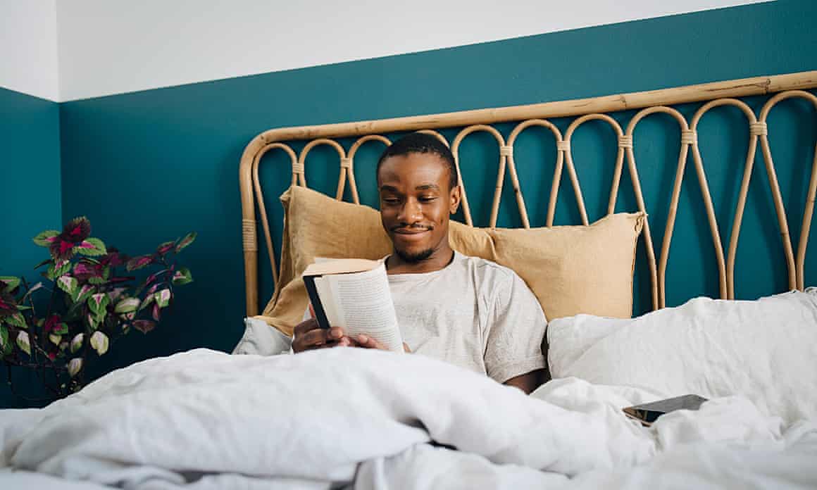 A man reading a book in bed