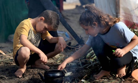Internally displaced Palestinian children light a fire to boil a kettle after overnight rainstorms in Khan Younis, in the southern Gaza Strip on 15 November.
