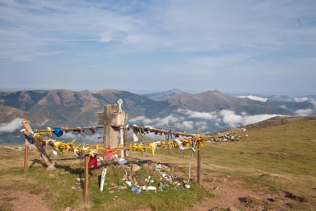 Shrine with little flags on a peak in mountains with clouds in the valley below.