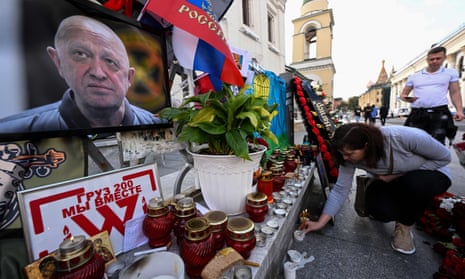 A woman lays a candle at a makeshift memorial for  Yevgeny Prigozhin in Moscow