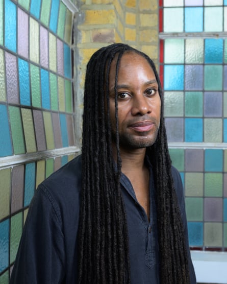 Jason Arday standing next to windows made of small panes of coloured glass