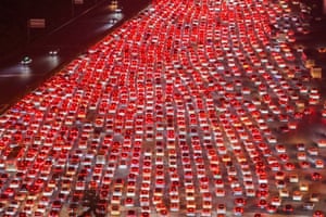 A aerial night shot of the brake lights of dozens of lanes of cars caught in a traffic jam