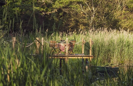 Chairs on deck overlooking reeds near stream.