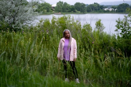 Woman in pink and purple standing in greenery in front of a lake