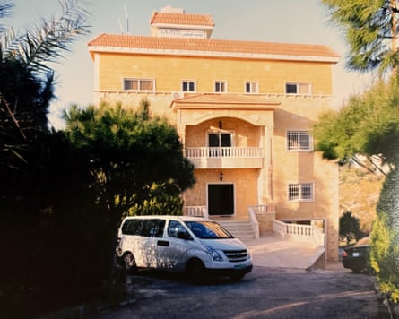 A small terracotta-coloured hotel building with a car parked in front