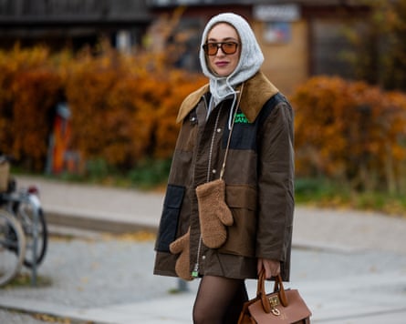 Sonia Lyson wears Falke tights & socks, shorts Sezane, Cos pullover, Ganni x Barbour jacket, Vehla sunglasses, grey knitted hooded hat H&M, brown Ferragamo bag, Max Mara teddy gloves on 26 November 2024 in Berlin, Germany