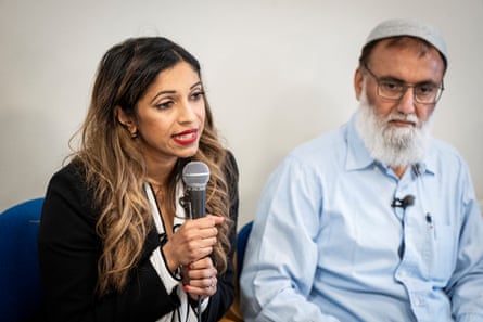 A woman speaks holding a microphone while a man sits next to her