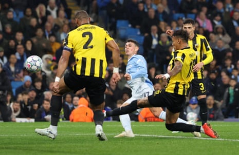 Phil Foden kicks the ball between AEK Athens defenders to score during a Champions League match