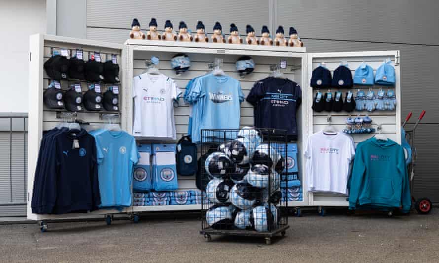 A Manchester City merchandise stall set up inside the Manchester City Academy Stadium.