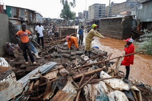 People looking through piles of rubble on the side of a muddy river