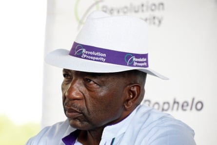 A man in a white panama hat with a purple ribbon around it on which the slogan 'Revolution for Prosperity' is written.