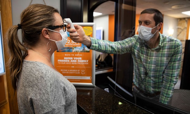 A dentist office manager takes the temperature of a woman as Ohio implements phase one of reopening dentists, veterinarians and elective surgeries on 1 May.
