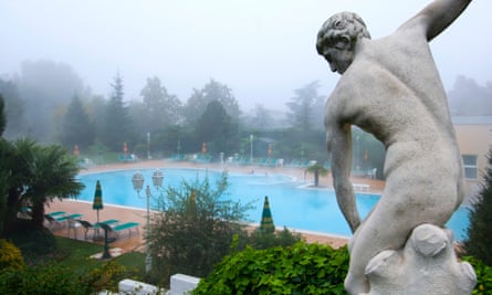 An outdoor swimming pool and a classical statue.