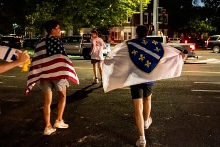 people walk outside carrying the flags of the US and Bosnia and Herzegovina