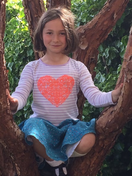 Marta Mills sitting in a tree, wearing a T-shirt with a big orange heart on it
