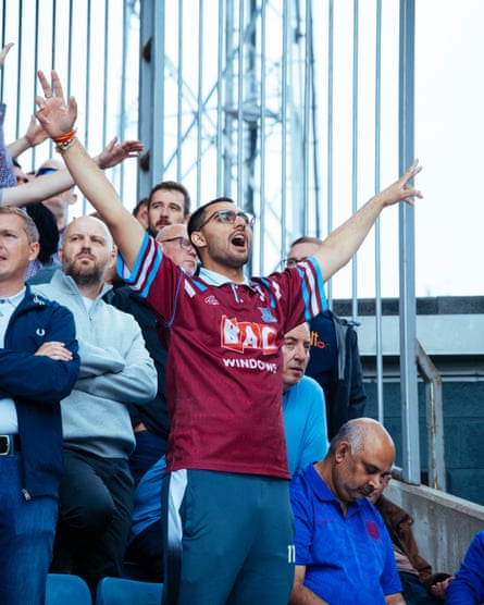 West Ham supporter wearing retro top sings with arms in the air