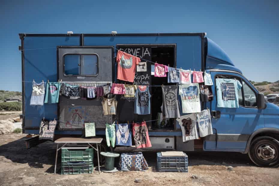 Mobile clothing stalls on trucks converted into houses in Praia do Amado parking lot.