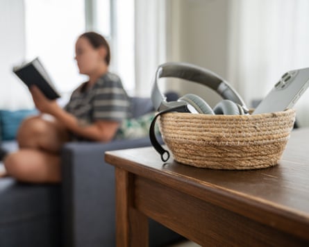 Woman reading on background. Basket with smartphone, smartwatch and headphones