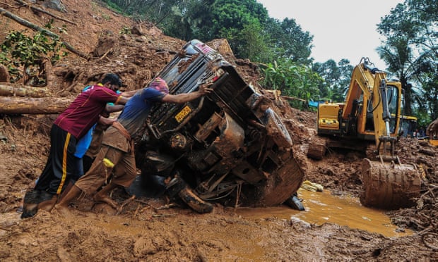 Rescue workers push an overturned vehicle stuck in the mud and debris at a site of a landslide following heavy rains in Kokkayar in India's Kerala state on Sunday.  