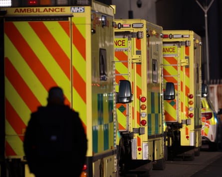 Ambulances line up outside a hospital as a person walks past