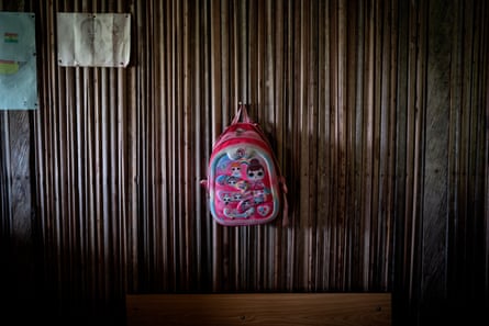 A child’s pink backpack hangs from a peg on a wall