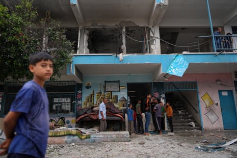 A boy looks on as a photographer takes a wider view of the damaged buildings.