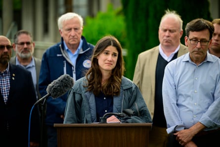 People stand with solemn expressions at a lectern