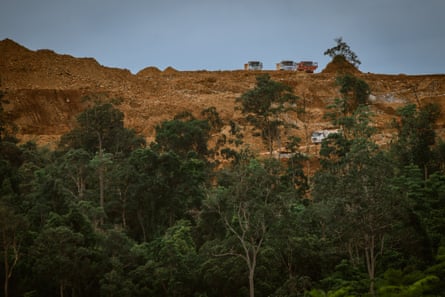 Three trucks on a ridge, with another truck on a road below them
