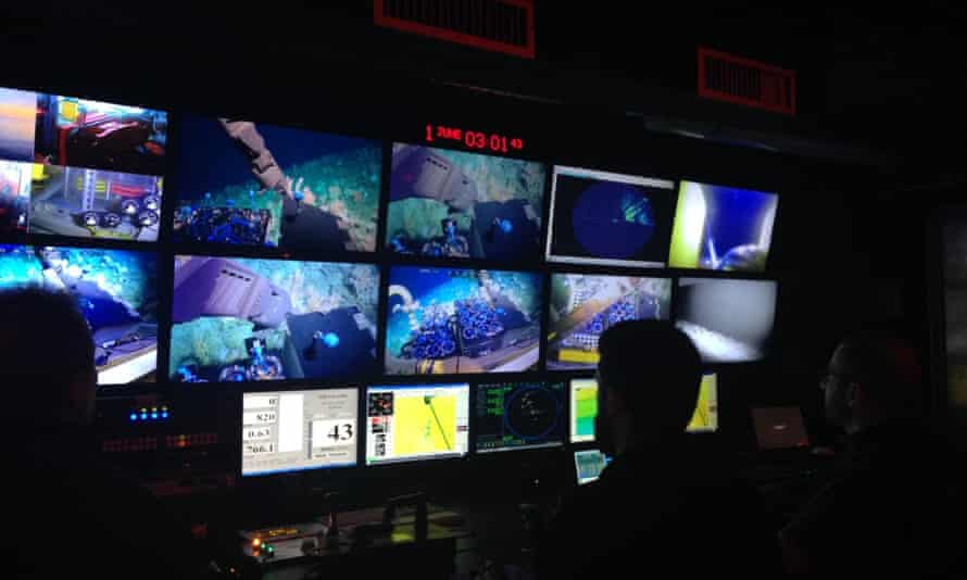 Scientists look at screens in a control room as they operate deep-sea submersibles remotely