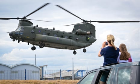 People watch from the sunroof of a car as an RAF helicopter takes off from Portland heliport.