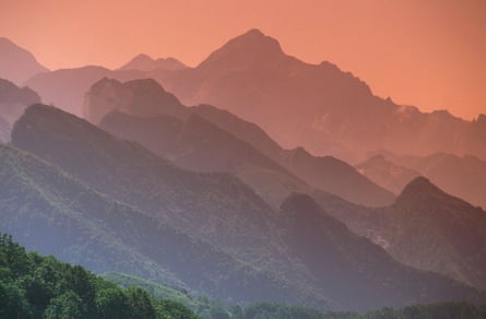 Misty sunset view of jagged mountains in red light