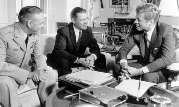Robert McNamara, center, talks with John F Kennedy and Maxwell Taylor, chairman of the chief joint chiefs of staff.