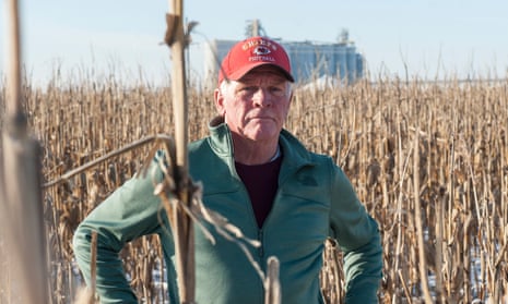 Richard Oswald stands in a frozen puddle surrounded by unharvested corn. Wet conditions have made harvesting difficult for Oswald and other farmers.
