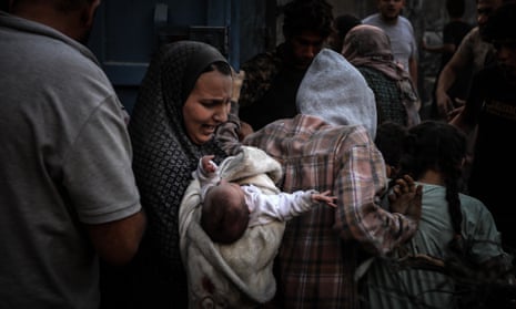 A woman cries over her baby after an Israeli attack on Al-Maghazi refugee camp in Deir Al Balah.