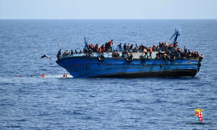 People jump out of a boat right before it overturns off the Libyan coast