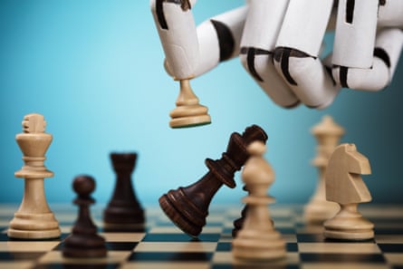 A close-up image of a white robotic hand moving a chess piece on a tan and dark brown wood board.