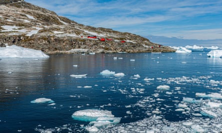The red buildings of a research station on a peninsula with icy water in Antarctica