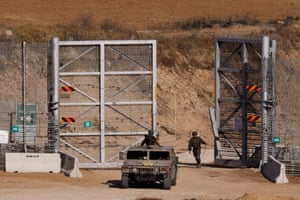 A soldier closes a gate at a border fence
