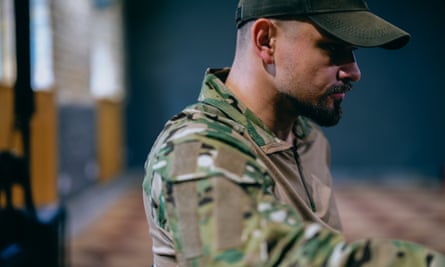 Maksym Devizorov, actor and soldier, sits side on in uniform at the Theatre of Veterans.