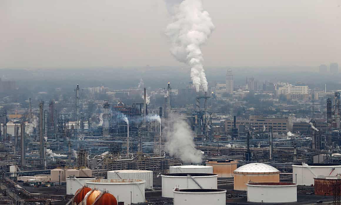 Emissions billow smoke stacks among holding tanks