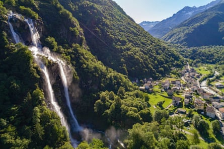 Waterfall cascading down a steep wooded mountainside into a valley