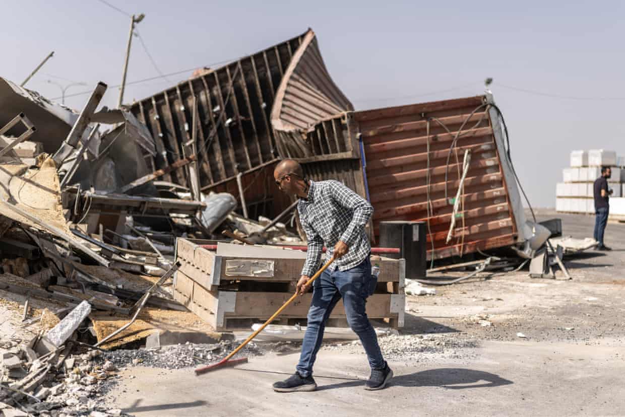 A Palestinian man sweeps rubble beside a demolished building in Hebron, West Bank