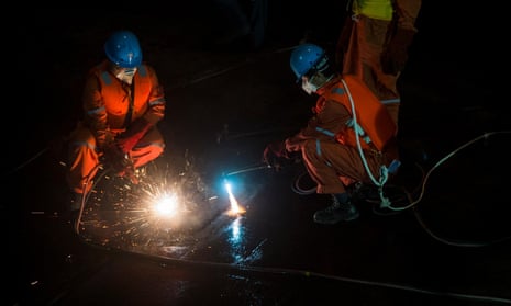 Rescue workers cut into the upside-down hull of the Eastern Star on Wednesday as they work around the clock at the capsize site in the Yangtze river. 