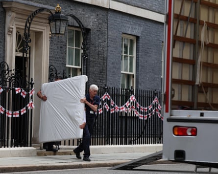 Removal workers carry a large item wrapped in white packaging towards a lorry