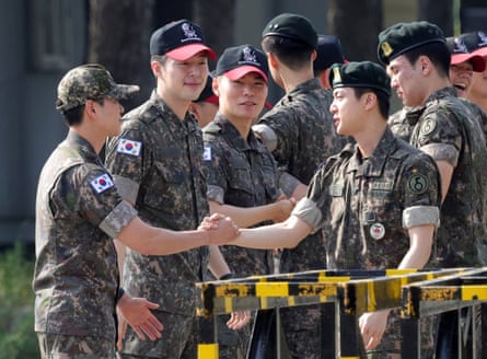 K-pop band BTS’s member Jin, front right, is greeted by other soldiers after being discharged