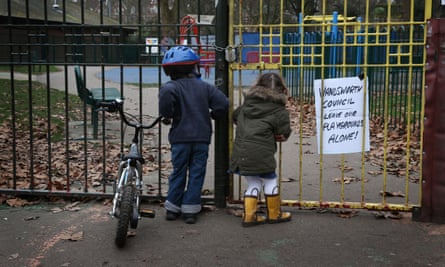 Children look into a closed playground next to Battersea Park, London.